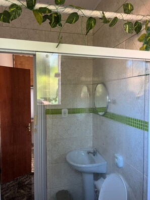 Ένα μπάνιο με ένα διαχωριστικό ντους από γυαλί, έναν νιπτήρα και μια τουαλέτα.