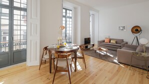 A spacious living area with a wooden dining table, a sofa, and a TV.