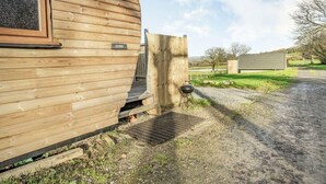 Una cabaña de madera con una puerta marcada con la leyenda "COTHI" y una parrilla en el exterior.