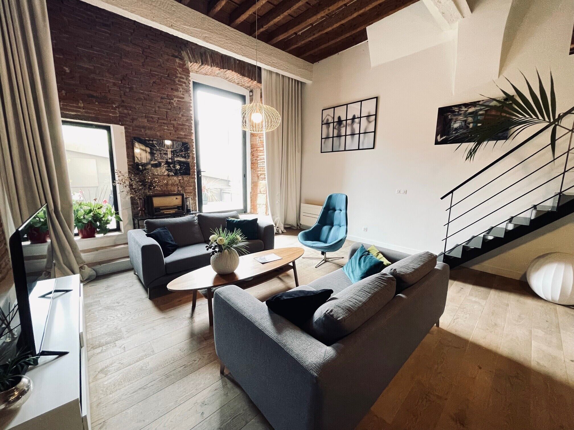 Un salon moderne avec un mur en briques, un escalier et une grande fenêtre.