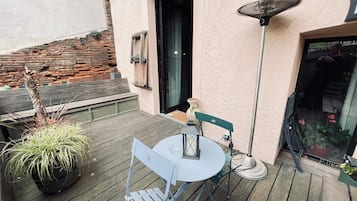 Une terrasse extérieure avec une table et des chaises, une plante en pot et un lampadaire.