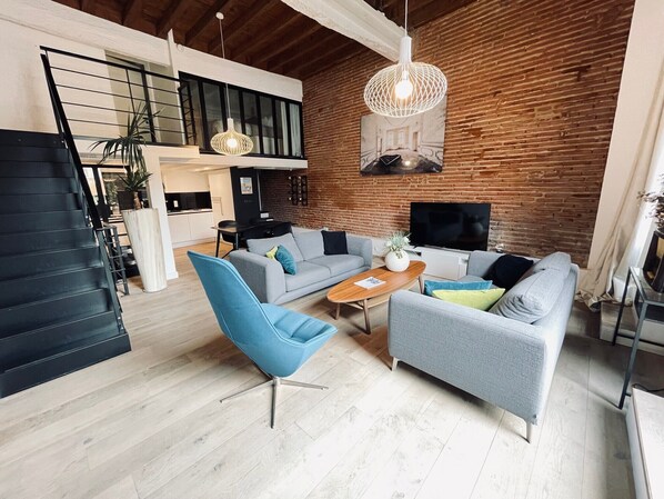 A modern living room with a sofa, armchair, and TV.