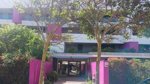 A building entrance with a covered walkway, surrounded by trees and a fence. - Beautiful T2 with pool - near beach (Palavas-les-Flots)