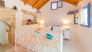 A bedroom with a stone wall, a bed with white bedding, a wooden ceiling, and a small bedside table with a lamp. - Thedreamhouse Chlorinefree Heated Pool Artvillage (Rhodes)