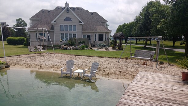 A backyard with a swimming pool, deck, and outdoor furniture.