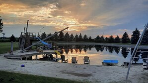 A lakeside park with a playground, picnic tables, and a wooden deck overlooking the water.