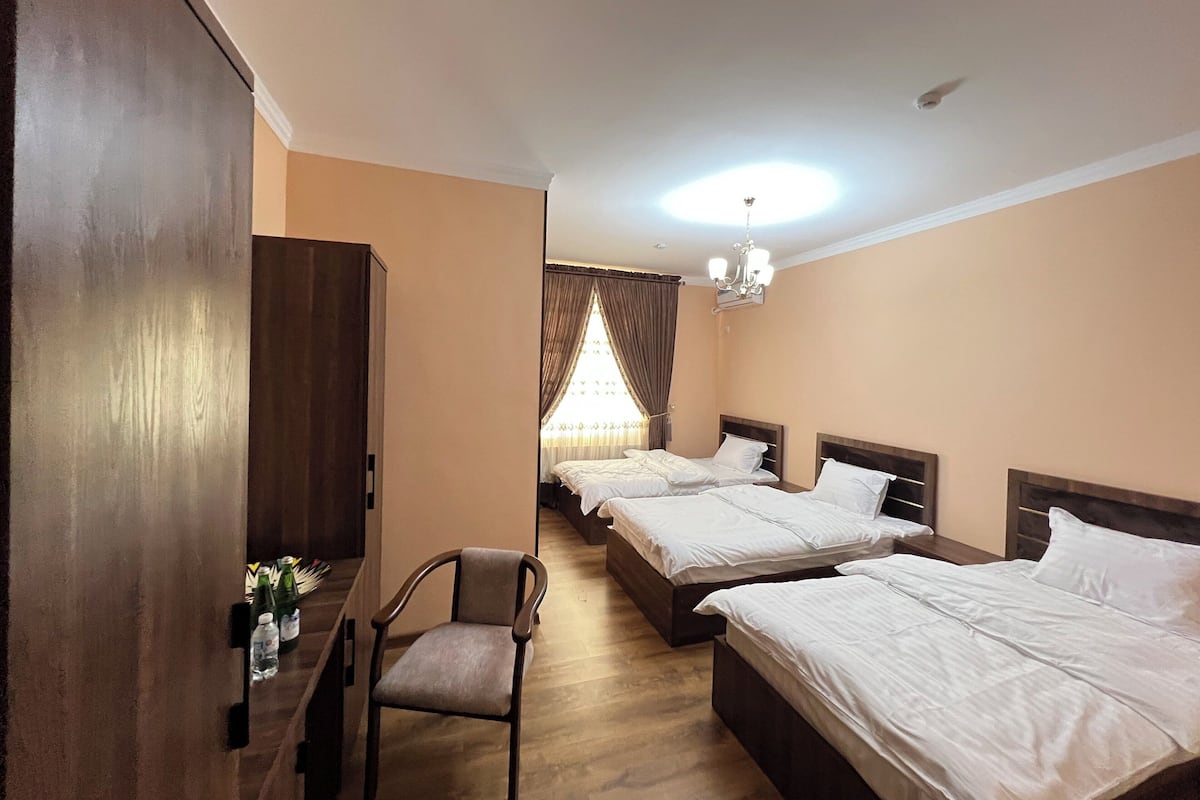 Habitación de hotel con dos camas, una silla, un armario y una araña.