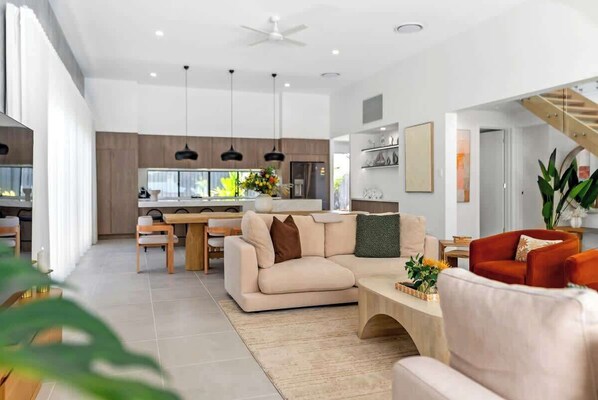 A modern living room with a sofa, coffee table, and a dining area with chairs and a table.