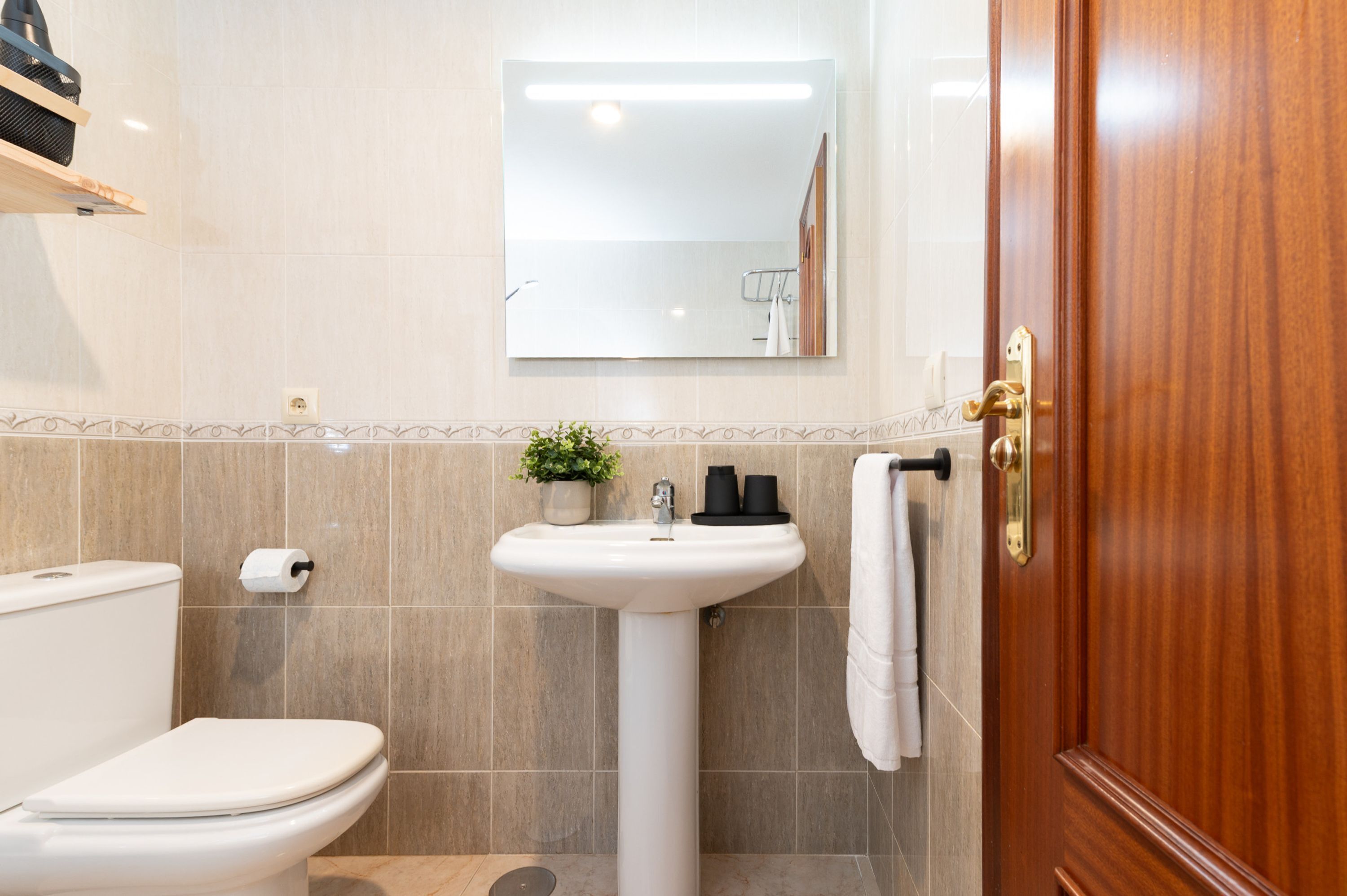 A bathroom with a toilet, sink, and mirror.