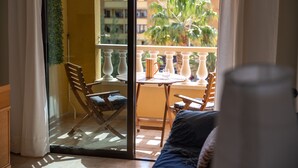 A balcony with a table, chairs, and a view of buildings and palm trees. - Las Olas Your Retreat in El M Dano (Granadilla de Abona)