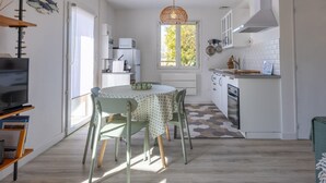 Una cocina compacta con comedor, televisor y ventana con vistas al verdor.