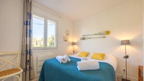 Un dormitorio con una cama, dos lámparas de noche, una silla y una ventana.