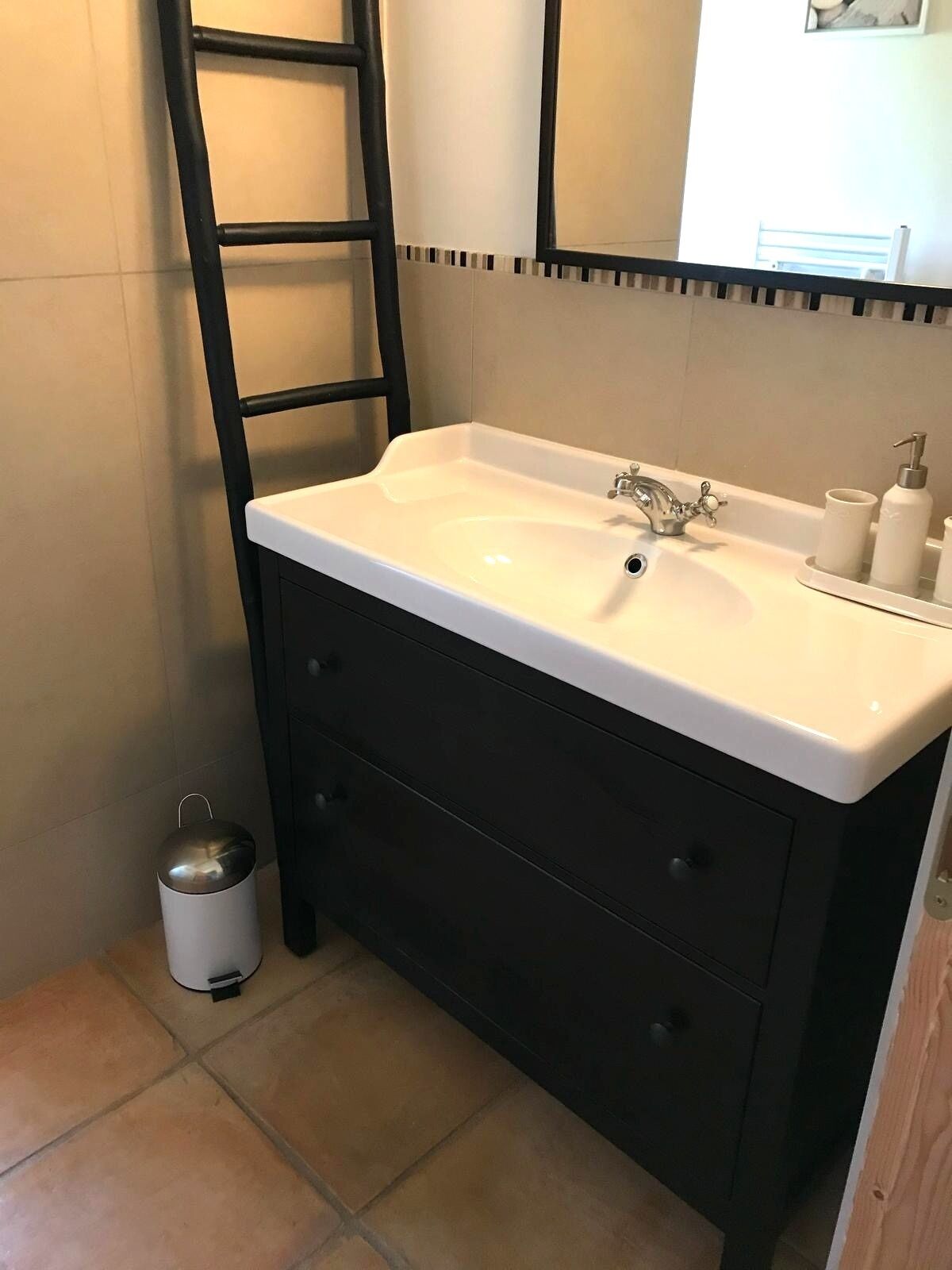 A bathroom with a white sink, black vanity, and a mirror above it.