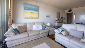 Una sala de estar con un sofá color crema, una mesa de centro y un cuadro en la pared.