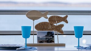 Una mesa dispuesta con un adorno de pescado de madera, dos vasos azules y un marco con el texto "COGOONR".