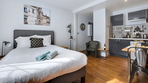 Ein modernes Hotelzimmer mit einem großen Bett, einer kleinen Küchenzeile und einem Esstisch.