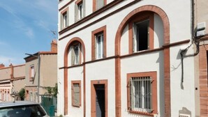 Ein zweistöckiges Gebäude mit weißer Fassade und roten Fensterrahmen.
