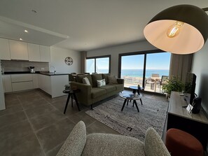 Un apartamento moderno con cocina, sala de estar y ventanas amplias que ofrecen vista al mar.