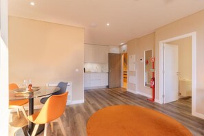A modern interior with a dining area, kitchen, and a hallway leading to a door. - CONDE13 Aparthotel Boutique  (Lisboa)