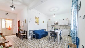 Un espacio habitable compacto con comedor, kitchenette y un sofá azul.