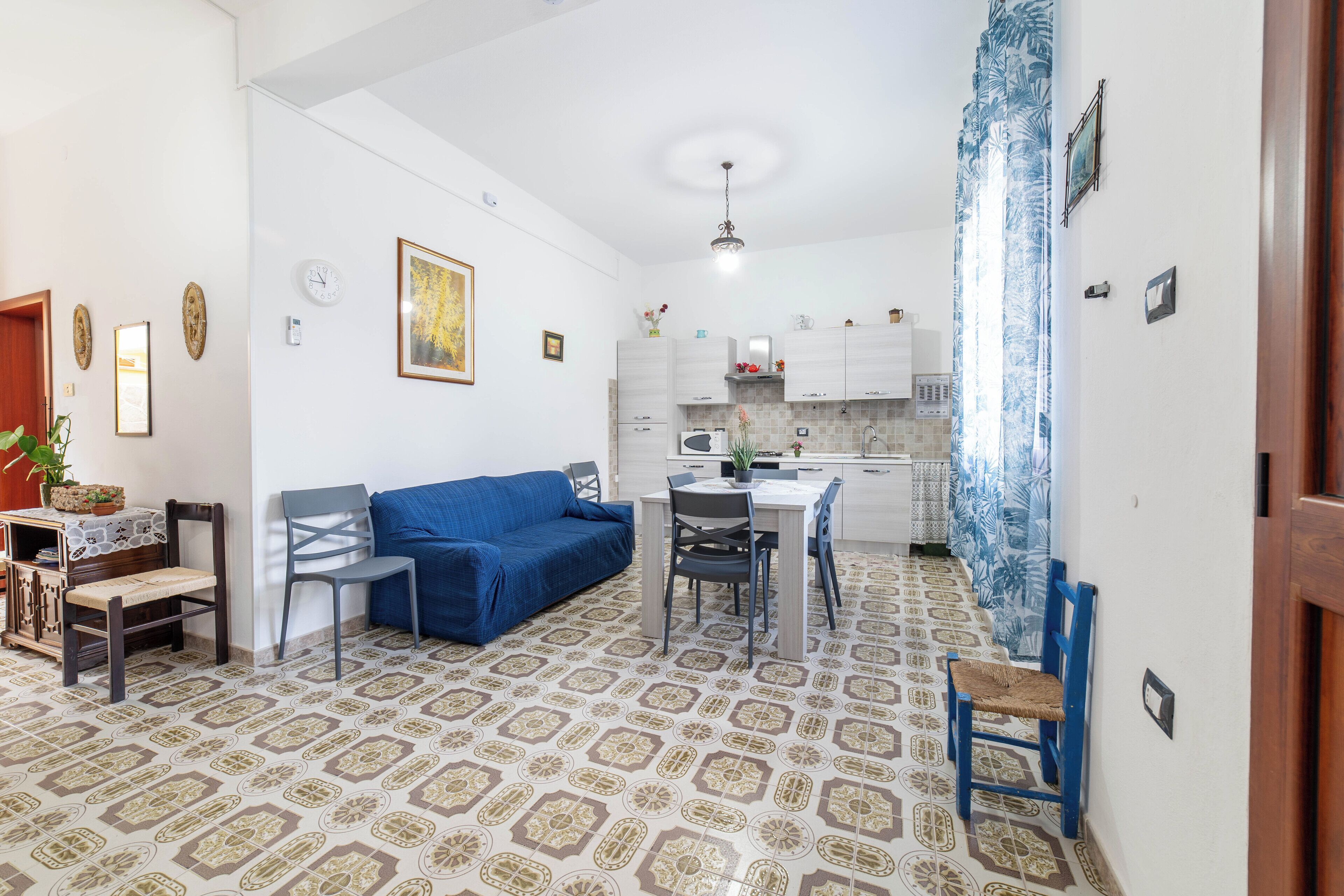 Un espacio habitable compacto con comedor, kitchenette y piso estampado.