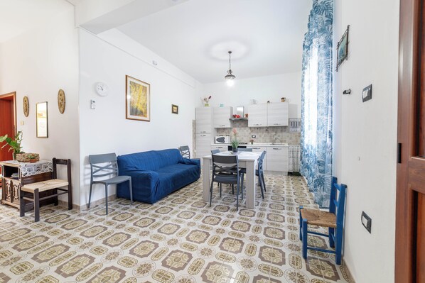 A compact living space with a dining area, kitchenette, and a patterned floor.