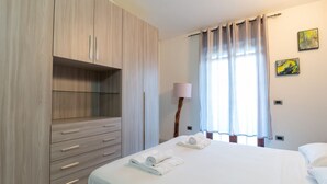 Ein Hotelzimmer mit Bett, Schrank, Lampe und zwei Bildern an der Wand.