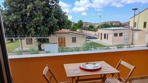 Ein Balkon mit Holztisch und -stühlen mit Blick auf eine Wohngegend mit Häusern und Bäumen.