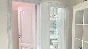 Un pasillo con puertas blancas que dan a un baño con ducha e inodoro.