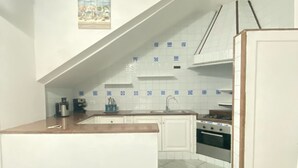 Una cocina compacta con armarios blancos, salpicadero de azulejos y una pequeña isla.