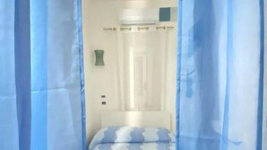 Una habitación con cama, cortina de ducha y toallero.