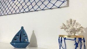 Una pared con un relieve de red azul, un velero de cerámica azul y una planta de cerámica en una maceta azul y blanca.