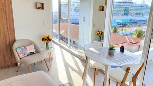 Ein Balkon mit einem weißen Tisch, zwei Stühlen, einer Couch und einer Vase mit Sonnenblumen.