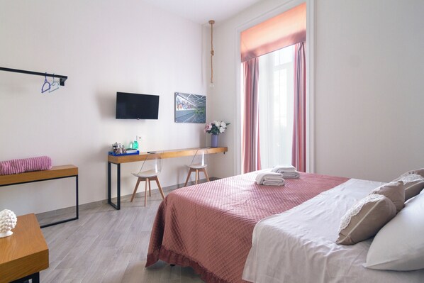 A bedroom with a bed, a desk, a chair, a TV, and a window with curtains. - maison do re umberto (Naples)