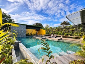 A swimming pool with a stone wall and a yellow building in the background. - Delfines del Golfo (Puerto Jimenez)