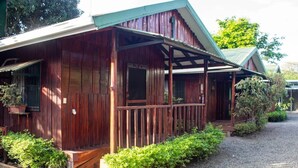 A wooden cabin with a porch, surrounded by greenery and gravel. - Delfines del Golfo (Puerto Jimenez)