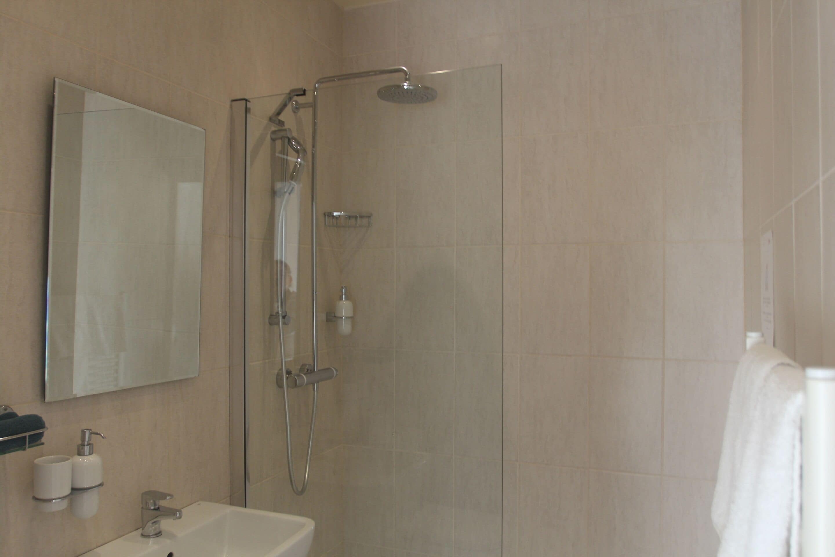 Un baño moderno con ducha de vidrio, lavamanos y espejo.