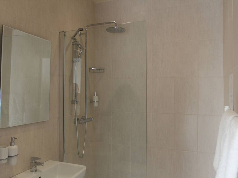 Un baño moderno con ducha de vidrio, lavamanos y espejo.