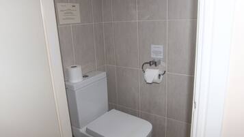 Un baño pequeño y limpio con inodoro, dispensador de toallas de papel y secamanos.