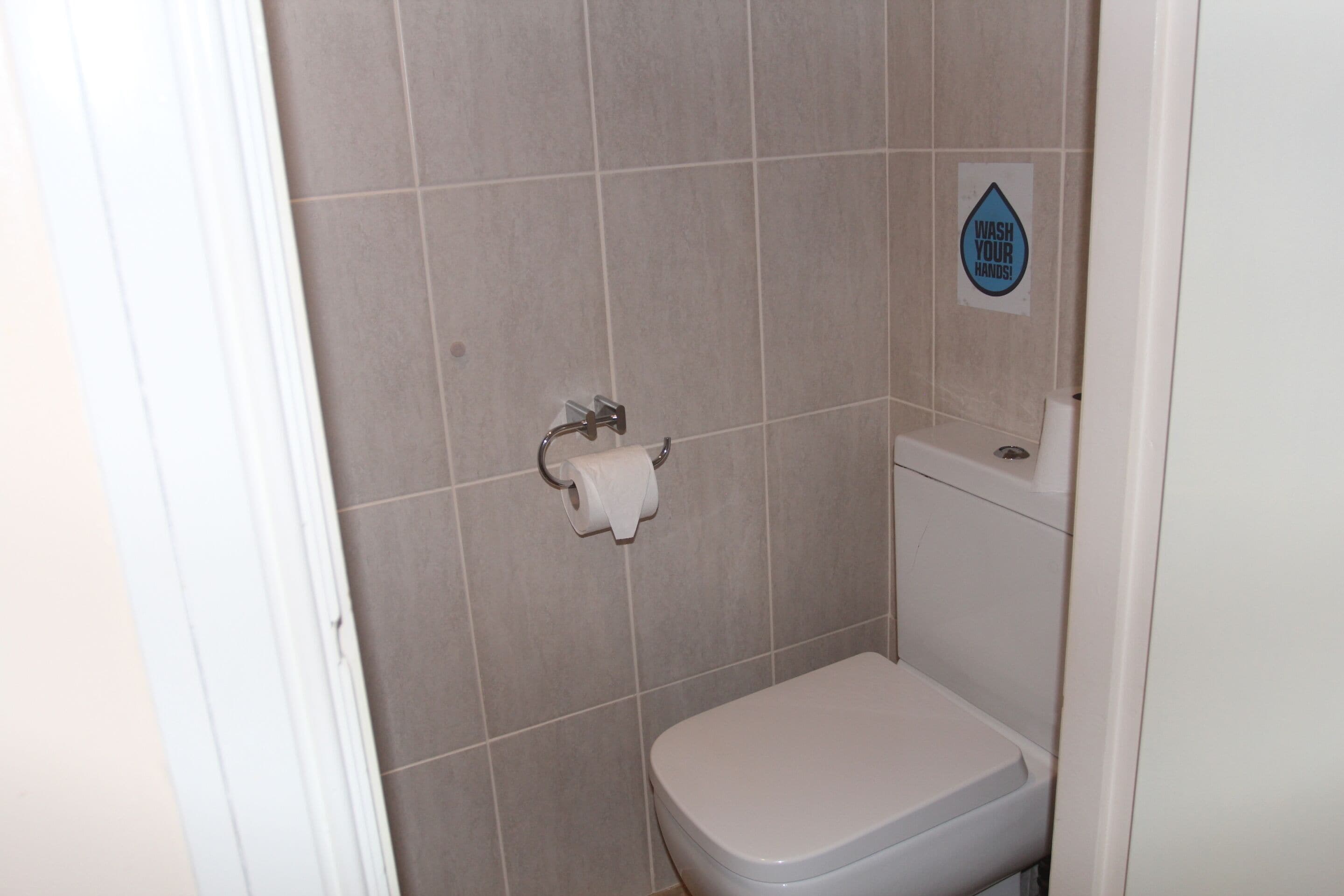Un baño pequeño con azulejos, un inodoro y un dispensador de toallas de papel.