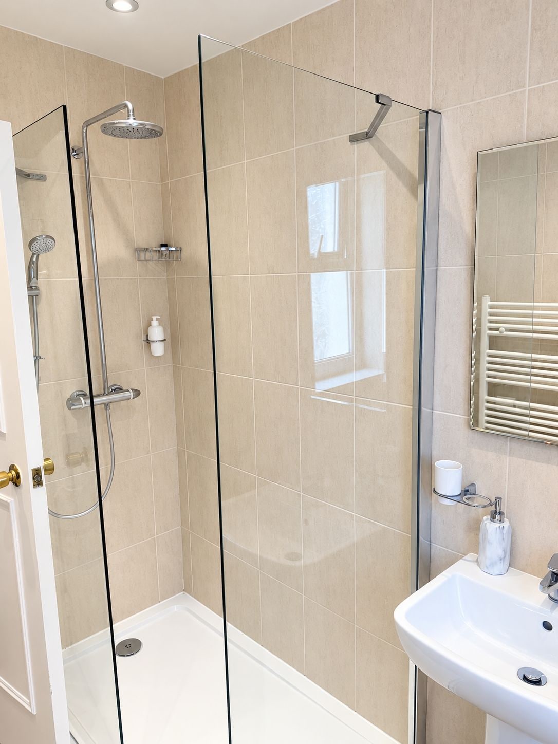 A modern bathroom with a glass-enclosed shower, a white sink, and a mirror above the sink.
