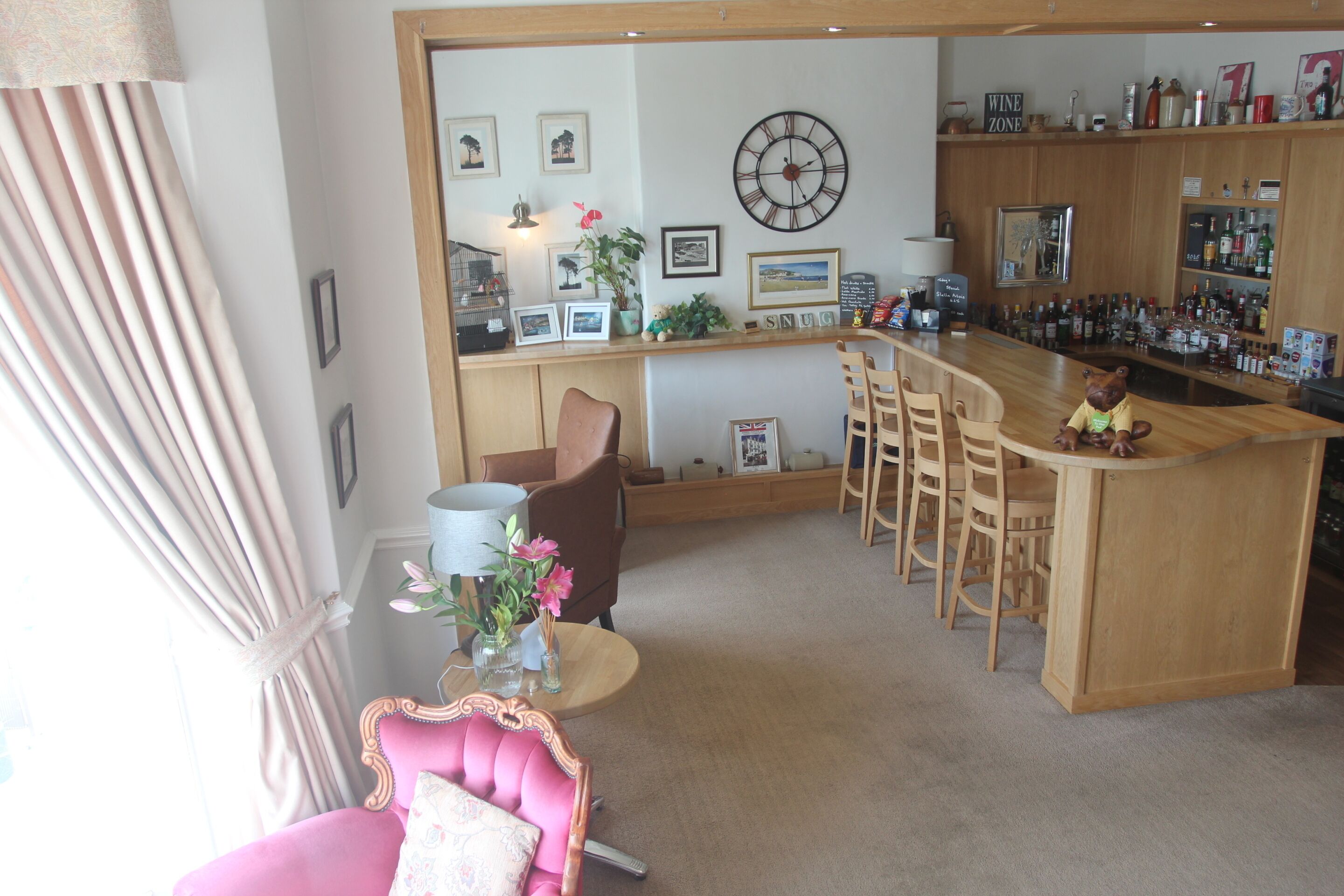 A bar area with wooden furniture, a clock, and framed pictures on the wall.