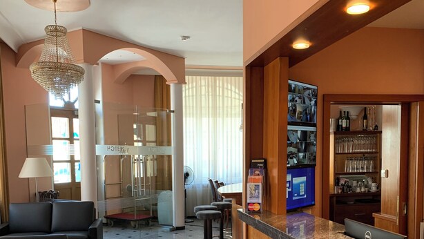 Een hotel lobby met een receptiebalie, een zithoek en uitzicht op de gang.