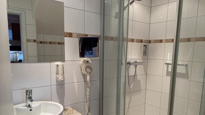 Een moderne badkamer met een wastafel van graniet, een douchecabine van glas en een handdouche.