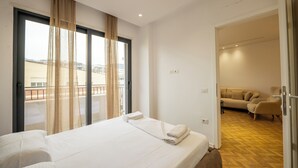 A hotel room with a large bed, a sofa, and a view of the city through the window. - Tirent Apartment-Modern 1-Bedroom Stay Near Liqeni i Thatë (Farke)