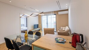 A modern hotel room with a glass dining table, black chairs, a red kettle, and a beige sofa. - Tirent Apartment-Modern 1-Bedroom Stay Near Liqeni i Thatë (Farke)