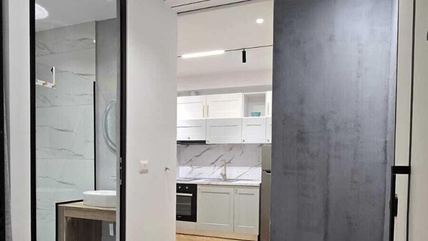 A modern kitchen with white cabinets, a marble backsplash, and a herringbone wood floor. - Tirent Apartment-Modern 1-Bedroom Stay Near Liqeni i Thatë (Farke)