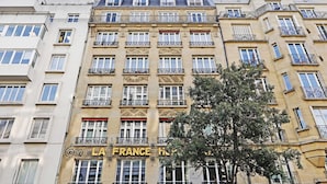 A multi-story building with balconies and a sign that reads "LA FRANCE HOTEL". - Appartement Beaubourg (Paris)