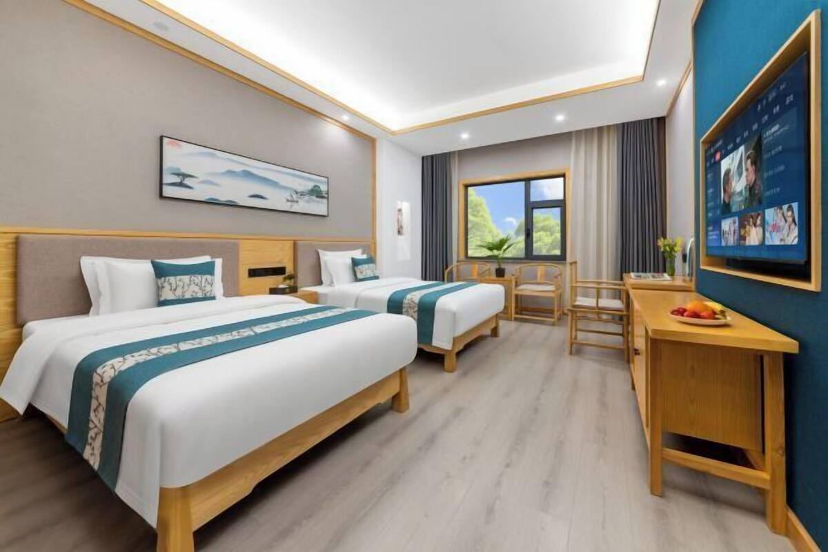 Ein Hotelzimmer mit zwei Betten, einem Schreibtisch, einem Stuhl, einem Fernseher und einem Fenster mit Blick.