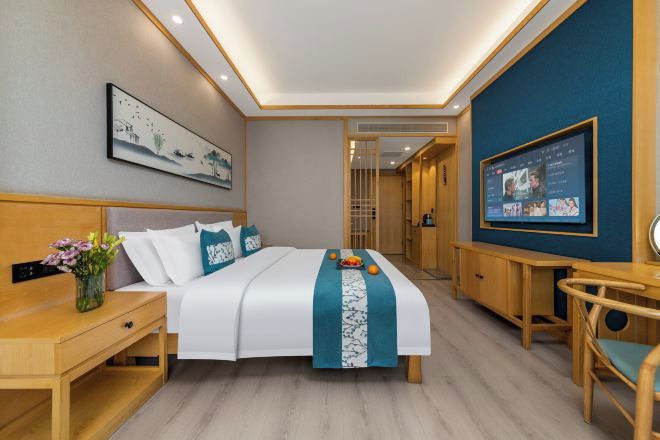 Una habitación de hotel con cama, mesita de noche, televisor y escritorio.